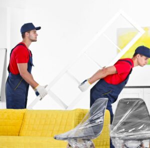 Umzug in Zwickau Zwei Helfer tragen ein Möbelstück an einem gelben Sofa vorbei – Umzug in Zwickau
