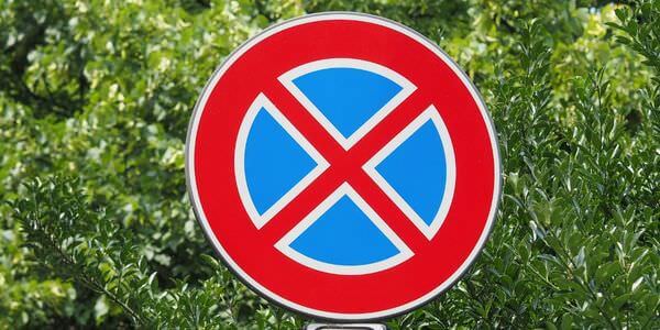 Rundes Halteverbotsschild vor grünem Laub – Stellplatz für den Umzugswagen