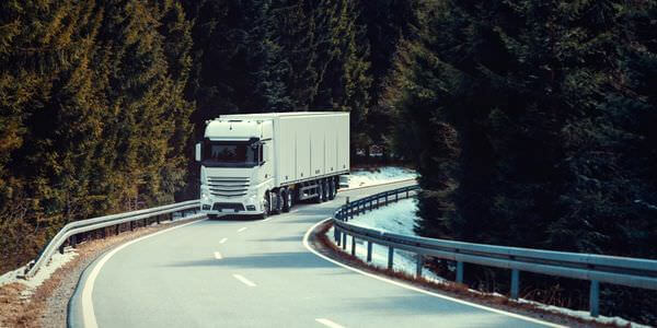 Klaviertransport Zwickau: Lkw fährt auf einer kurvigen Straße durch den Wald